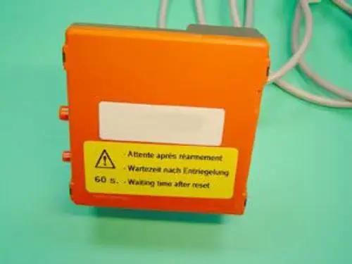 Remeha Gasfeuerungsautomat in Orange mit Anschlussmöglichkeiten. Beschriftung in mehreren Sprachen, einschließlich Warnhinweis und Anweisungen zur Wartezeit nach dem Zurücksetzen.